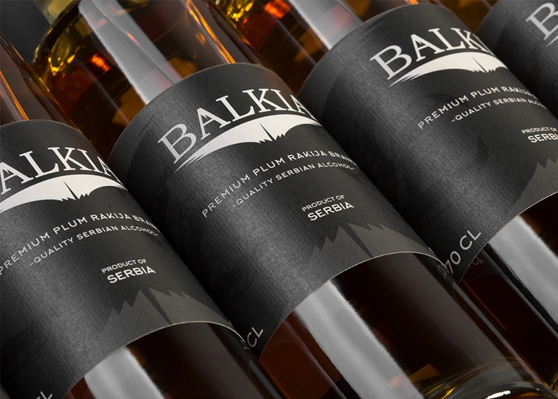 Gros plan sur des bouteilles de rakija de prune Balkia premium aux étiquettes noires, alignées